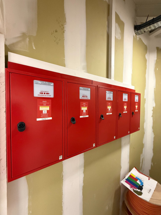 Pose et installation d'alarme et incendie avec coffrets rouges de sécurité dans un couloir technique